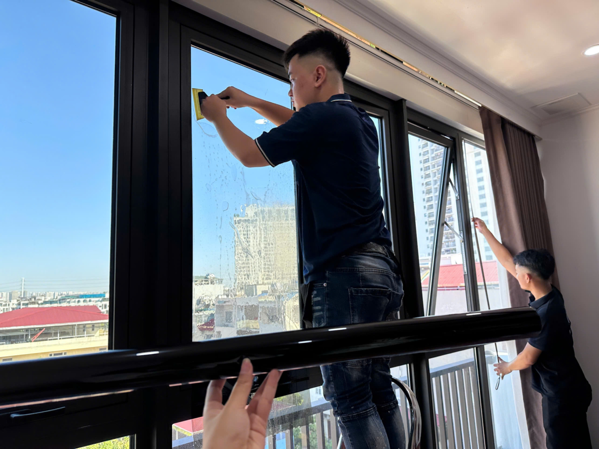 Kỹ thuật viên thi công phim cách nhiệt nhà phố trên cửa kính hướng Tây