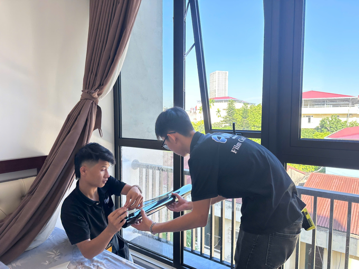 Hai kỹ thuật viên chuẩn bị phim cạnh cửa và rèm